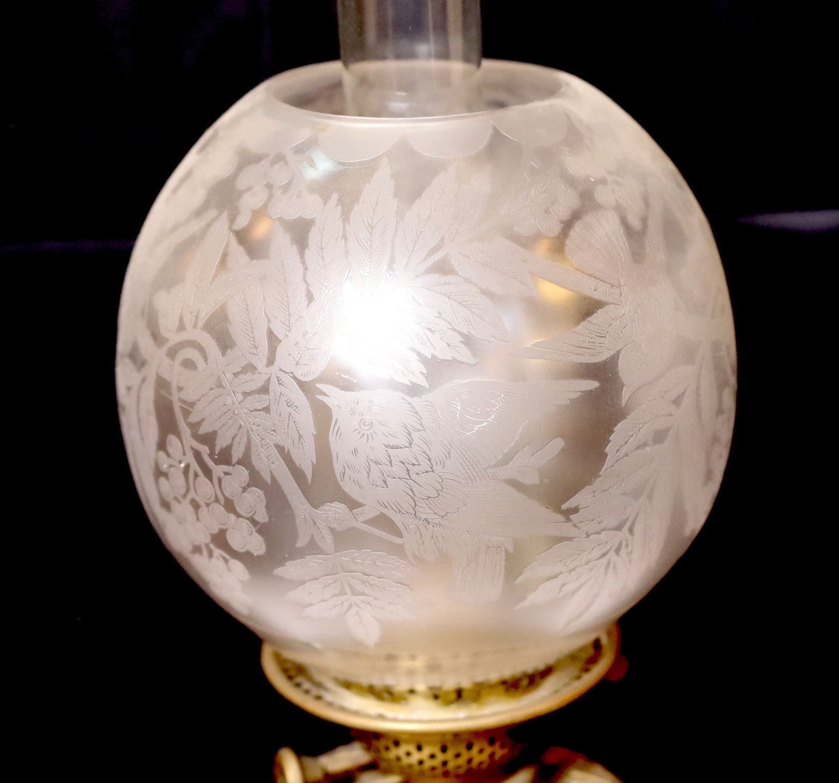 A Victorian brass mounted ceramic oil lamp in the manner of Dalton with brass reservoir and frosted glass shade decorated with birds, height overall 64cm